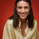 Yellow Twibbon Happy World Smile Day Facebook Post (1) | Watertown Dentistry Smiling woman with shoulder-length dark hair, wearing a cream polka-dot blouse and hoop earrings, posed against a red background.